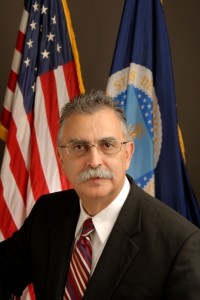 FSA Administrator Juan Garcia sitting in front of the American and USDA Flags